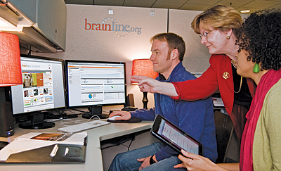 Brain injury advocate Rankin (standing) talks with BrainLine staffers Ian Collins and Krystal Klingenberg. (Photo: Brian King, BrainLine.) 