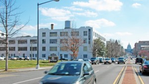 Traffic rushes north past NPR's new headquarters site (at left), above Capitol Hill and Union Station in Washington, D.C. The site's developer obtained site permission to tear down half of the history-landmarked warehouse and build an office tower behind it. (Photo: Steve Behrens, Current.)