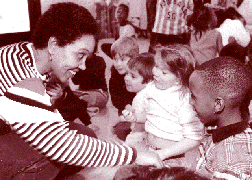 Young woman cajoles crowd of toddlers