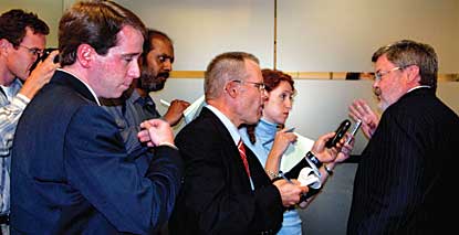 Journalists with cameras, recorders and notepads  pursue CPB chairman.