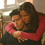 Actress hugs actor in rocking chair with atmospheric light from "window" in background